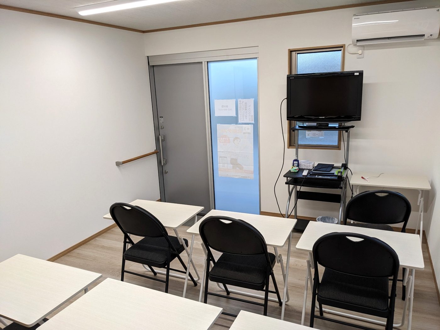 森田塾の教室。白い机と黒い椅子が並び、前にモニターがあります